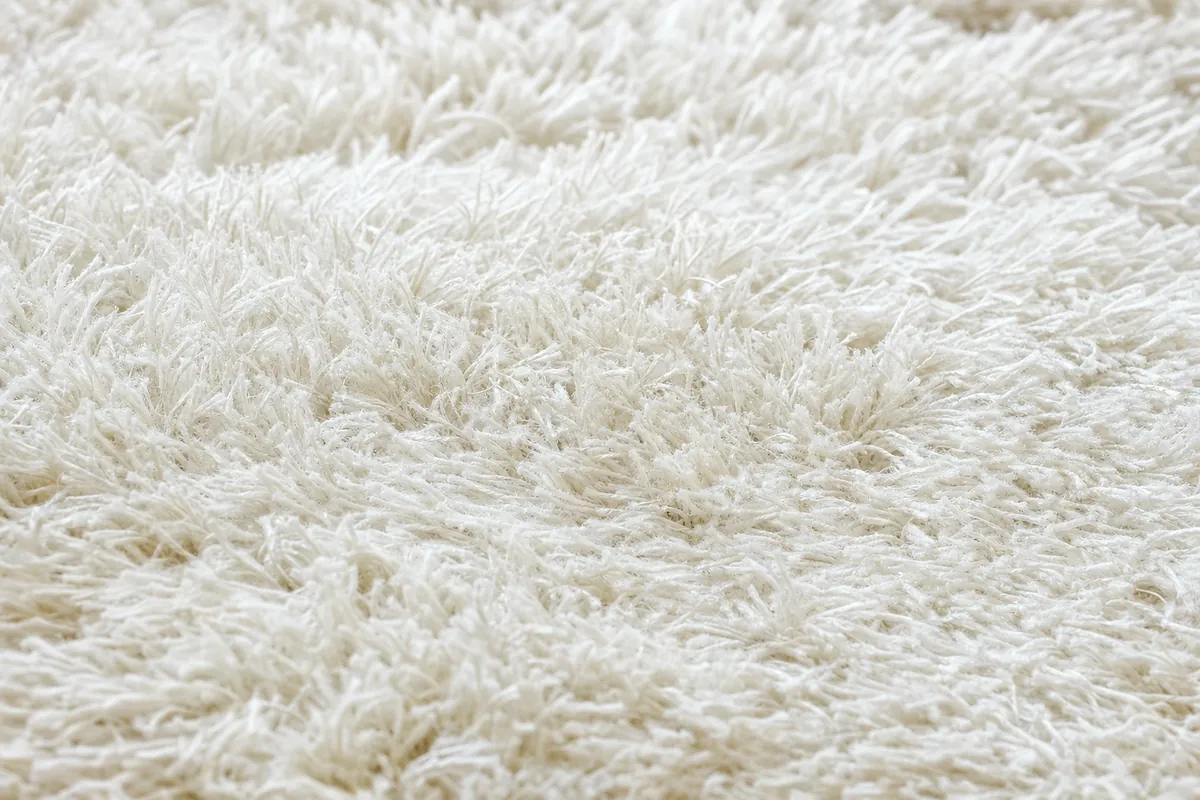 Close up of high pile shaggy carpet texture in cream white with deep soft fibres